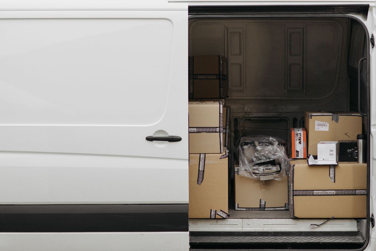 De open schuifdeur van een witte bestelwagen, met gestapelde dozen in de laadruimte